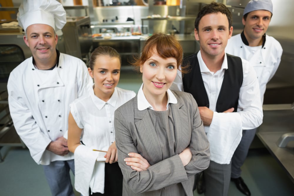 Manager posing with staff in a modern kitchen